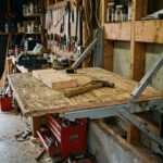 Fold-down workbench with metal brackets in a cluttered woodworking garage workshop